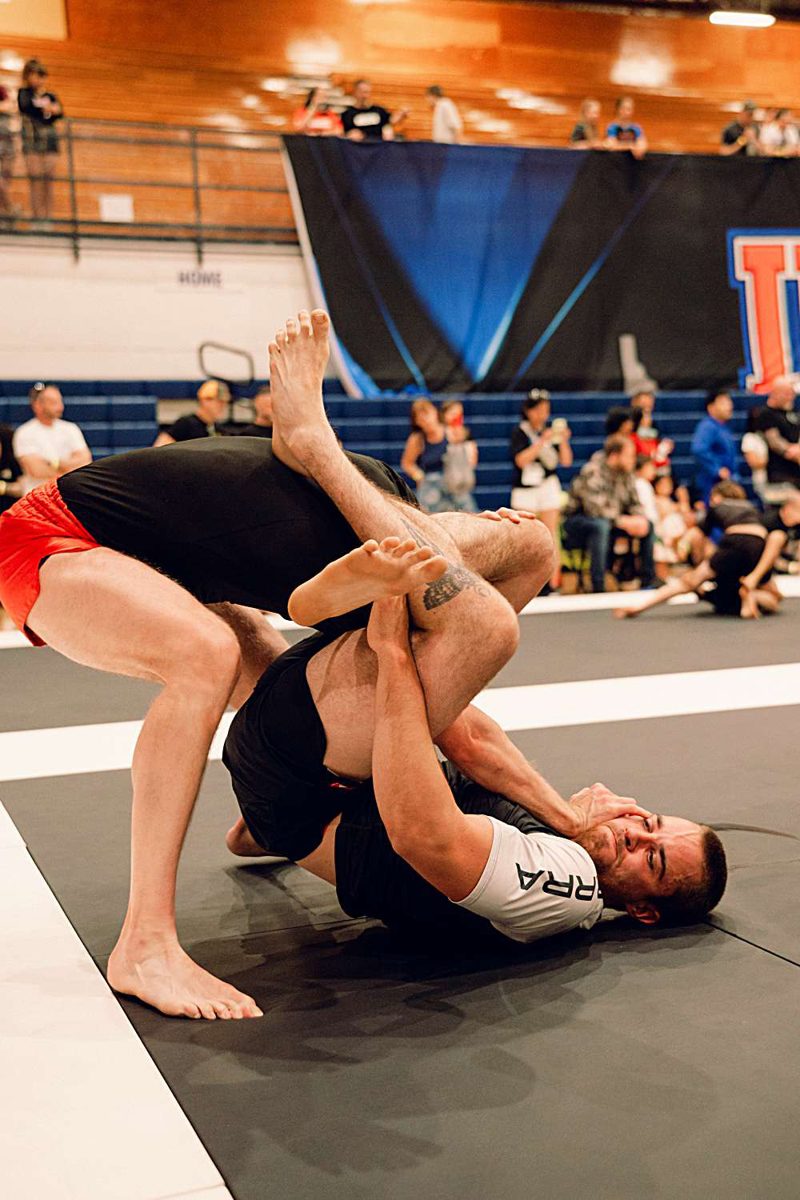 Athlete locking up a submission mat-side in front of the crowd
